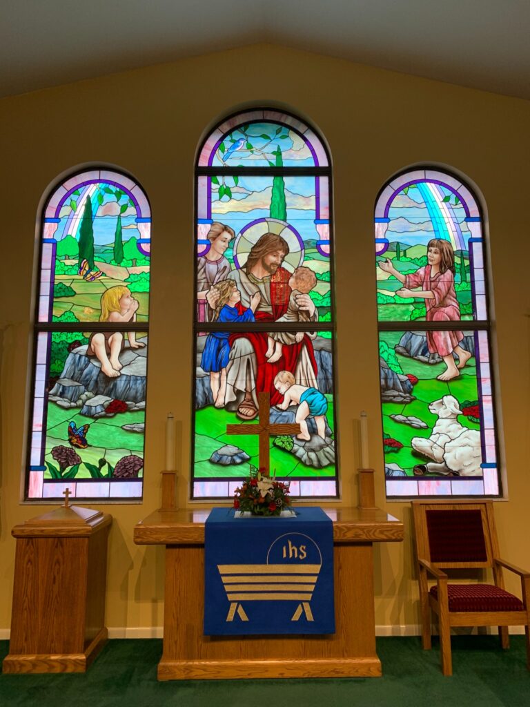 stained window of Jesus welcoming children in church